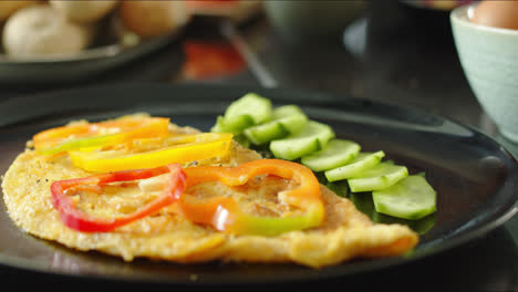 close-up of man garnishing omelet with diced peppers