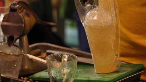 bartender mixes and serves a cold beverage in a glass.