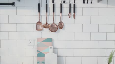 a bright, minimal kitchen wall features copper utensils, geometric cutting boards, cookbooks, herbs, and fresh produce arranged with clean aesthetics.