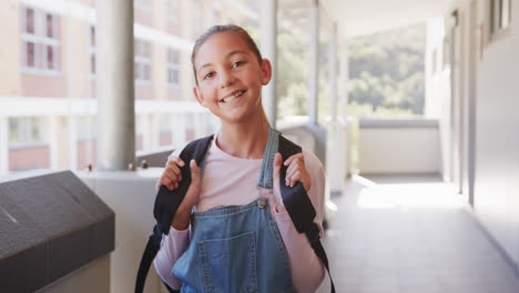 smiling girl with backpack standing in school hallway, ready for class