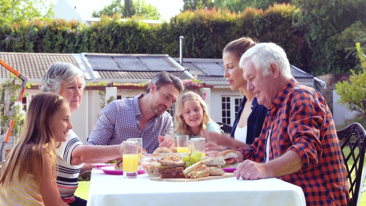 여러 세대의 가족이 정원에서 식사를 하고 있습니다.
