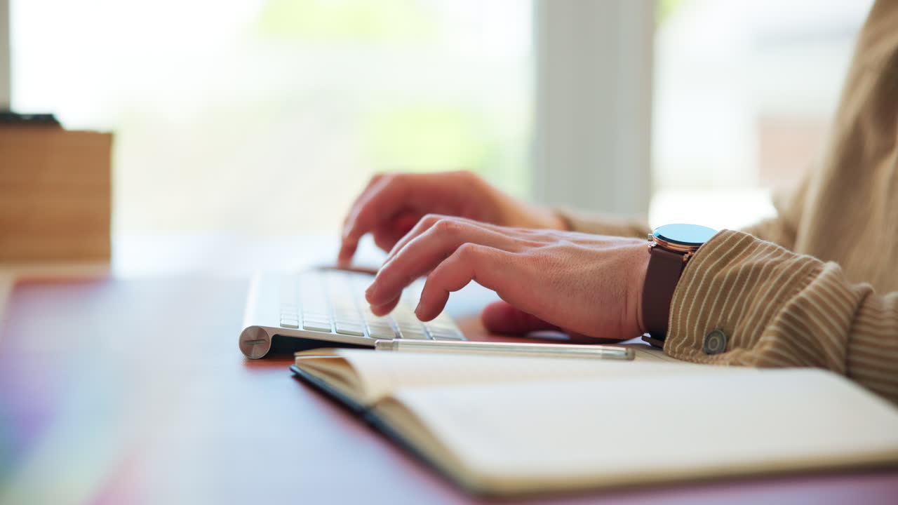 Primo piano di mani che digitano su una tastiera di computer a una scrivania