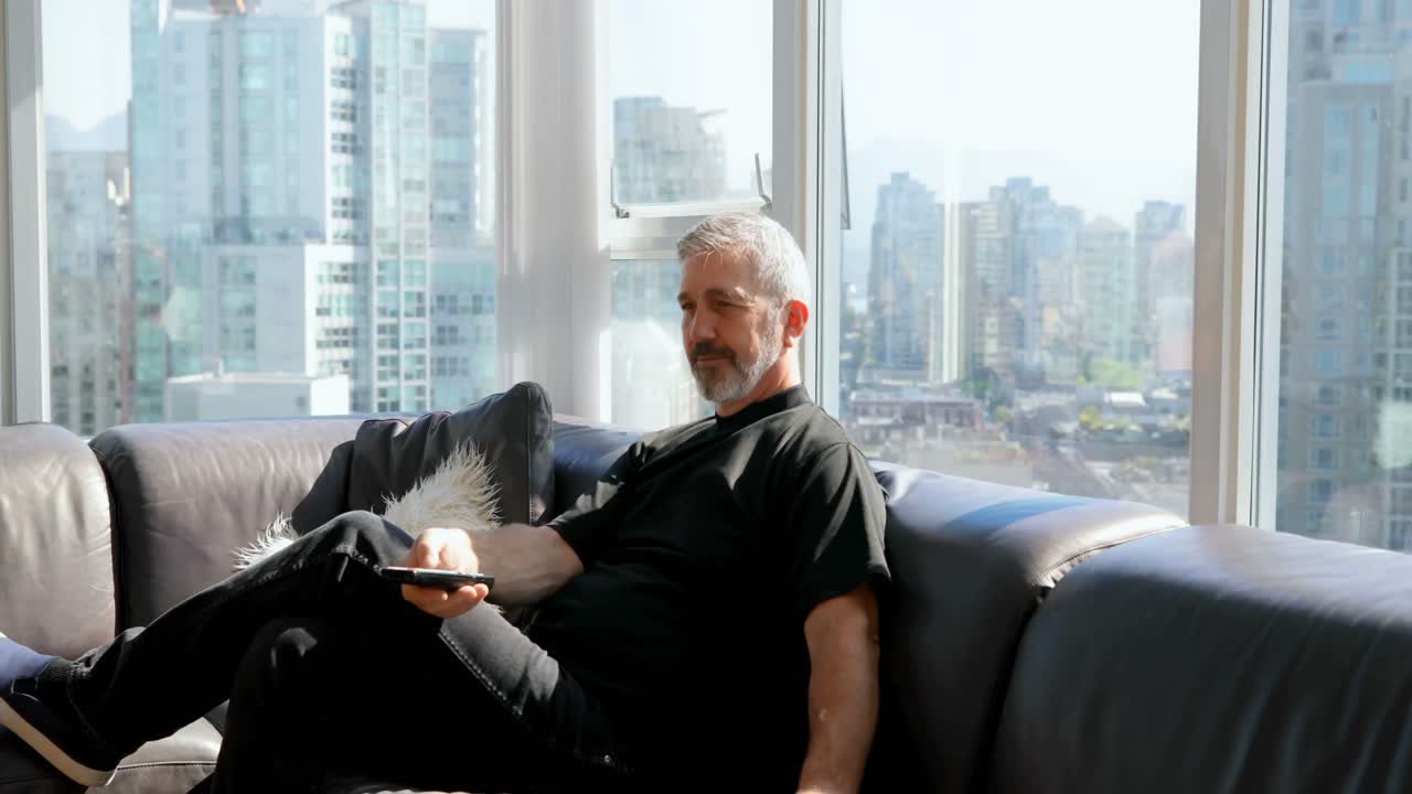 소파 4k에서 리모컨을 사용하는 사람