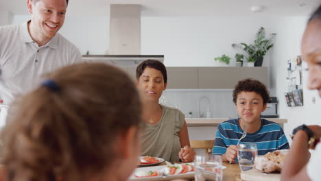 Multi-Generation-Mixed-Race-Family-Eating-Meal-Around-Table-At-Home-Together