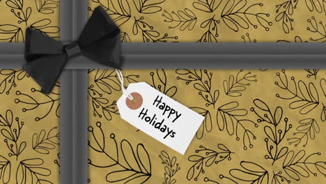 animation of happy holidays text on tag over christmas present with black ribbon