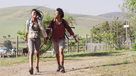 feliz pareja afroamericana con mochilas, caminando juntos en un día soleado, cámara lenta