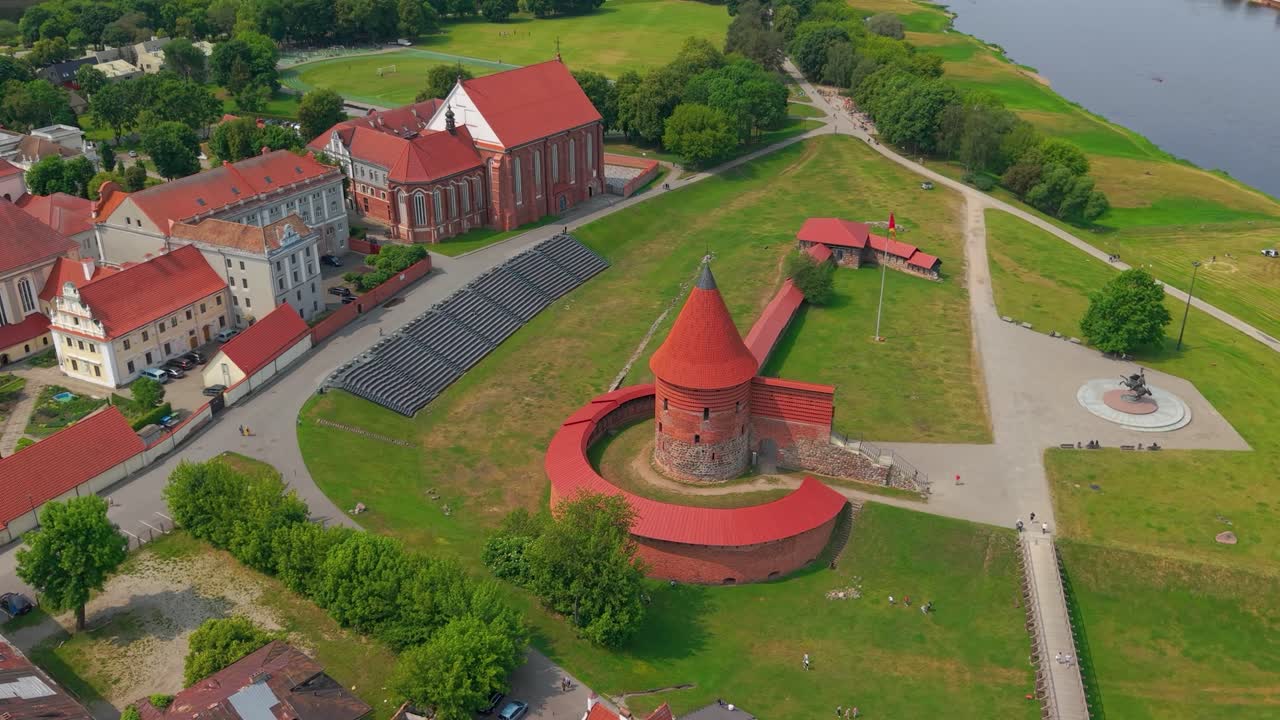 Aerial view of Kaunas Castle and surrounding historic buildings near the river in Kaunas, Lithuania, showcasing medieval architecture and urban landscape on a summer day