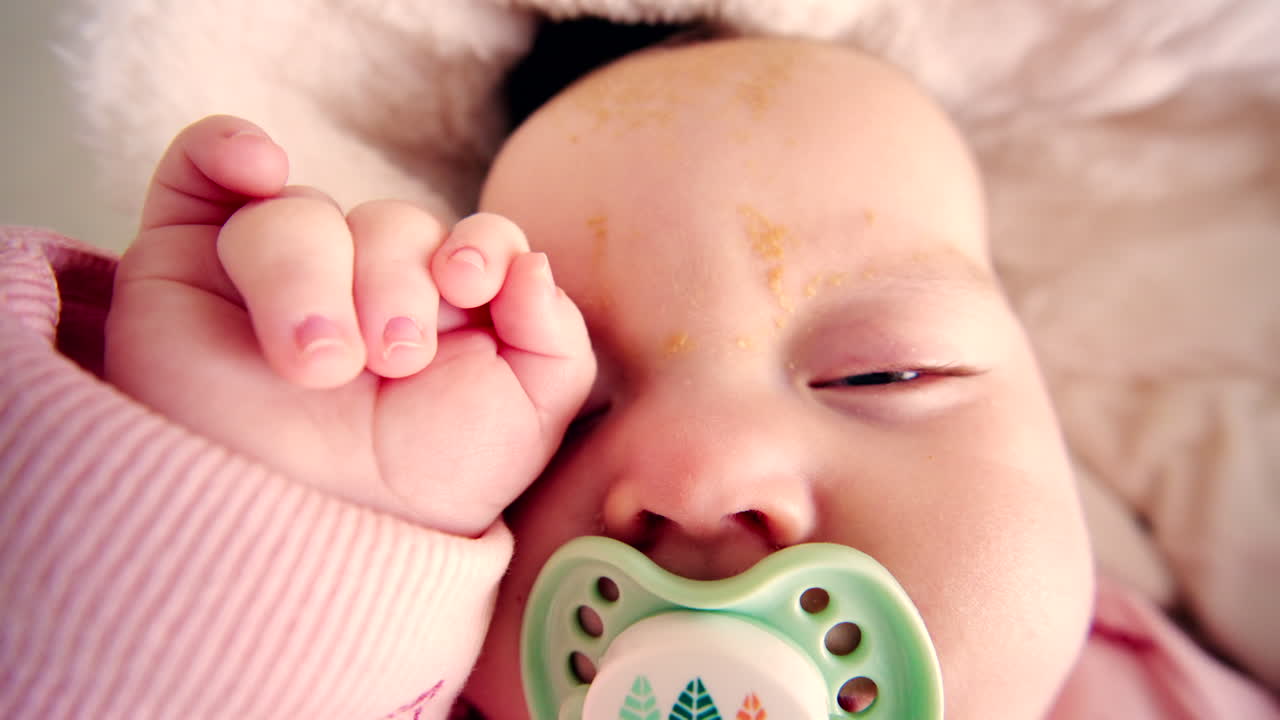 Close up of a newborn baby sleeping peacefully while sucking on a pacifier