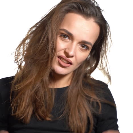 a mysterious woman with brown eyes in a black jumper straightens her magnificent hair on a white background in the studio.