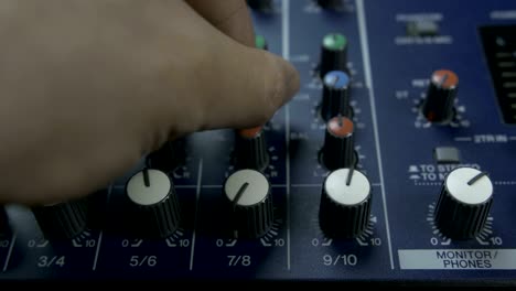 male fingers turning knobs on audio mixing desk