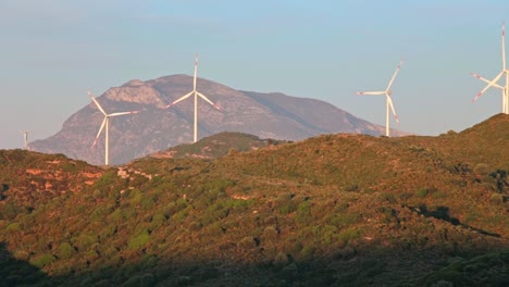 idyllic landscape of mountainous aegean turkey and quickly rotating blades of wind power turbine plants among sunlit hills, datça peninsula