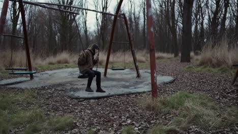 a girl on an abandoned swing set in a deserted park