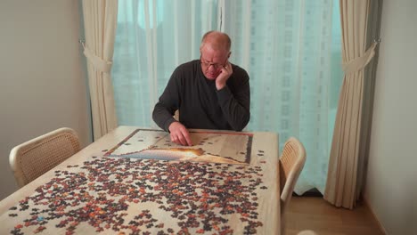 single, senior man works on a puzzle at home to pass the time