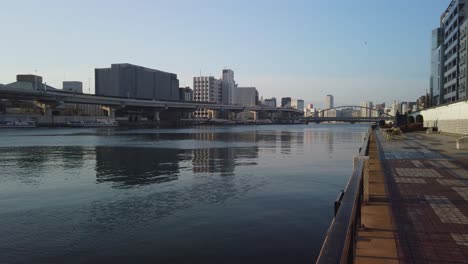 Sumida-River-walk,-pan-across-Tokyo-establishing-shot-at-sunrise