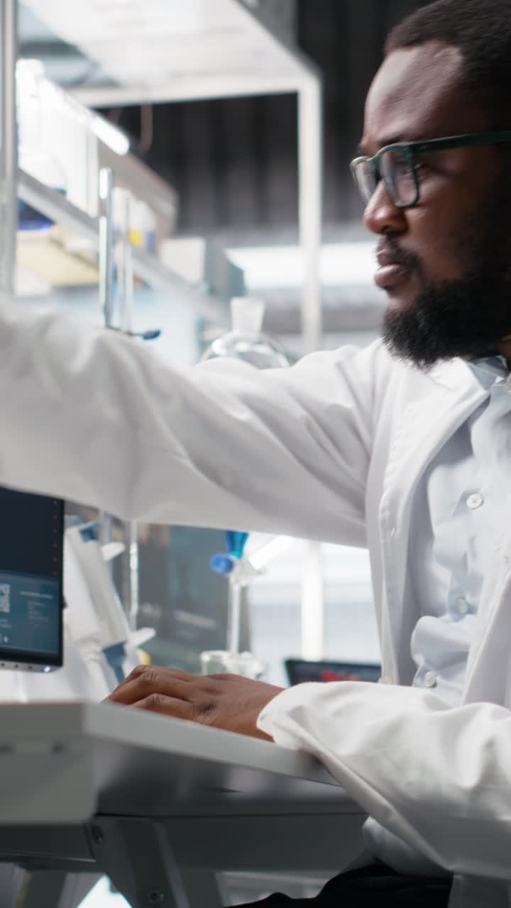 Vertical video Quality control analyst in laboratory analyzing solution at workstation using PC