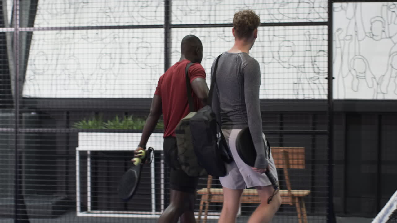Players preparing for padel tennis match on blue indoor court, holding rackets