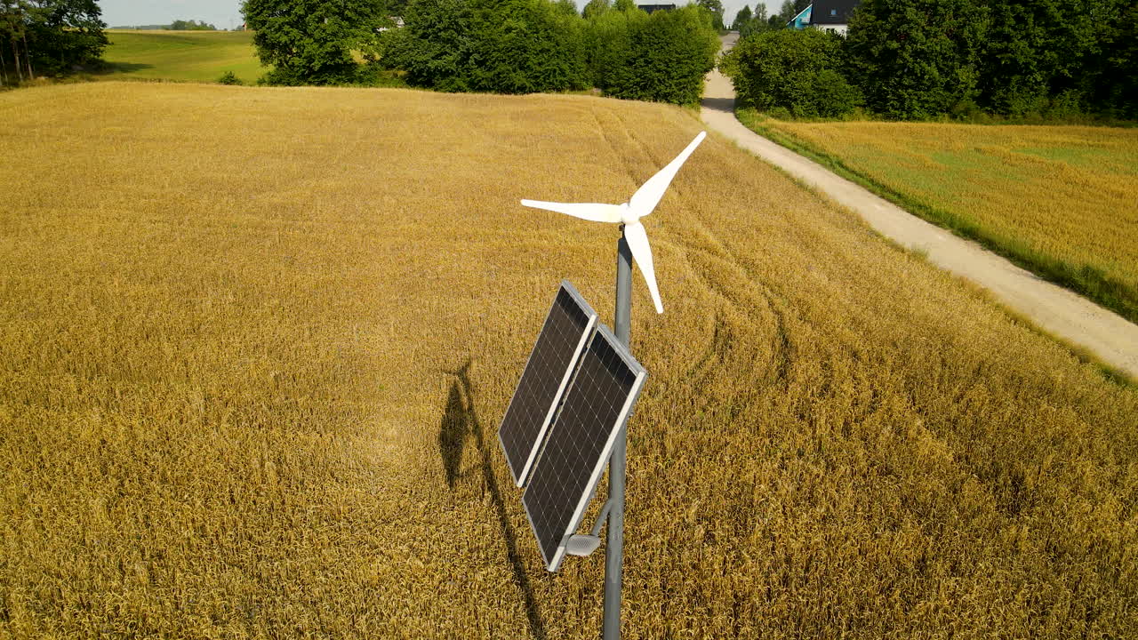 Palo di illuminazione autonomo con generatore eolico e pannello solare vicino a un campo di grano giallo nella campagna di Czeczewo, Polonia, panoramica aerea