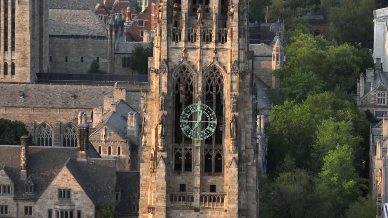 Harkness tower in Collegiate Gothic architecture on campus of Yale university. Sunset time in New Haven, Connecticut. Aerial zoom shot. Historic houses and homes in background