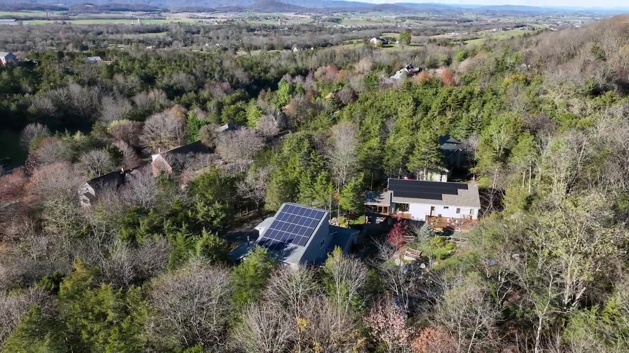 Moderne enfamiliehuse med solpaneler mellem farverige træer om efteråret. Idyllisk forstadslandskab i Virginia på en solrig dag. Tema: Produktion af grøn energi. Luftfoto ovenfra.