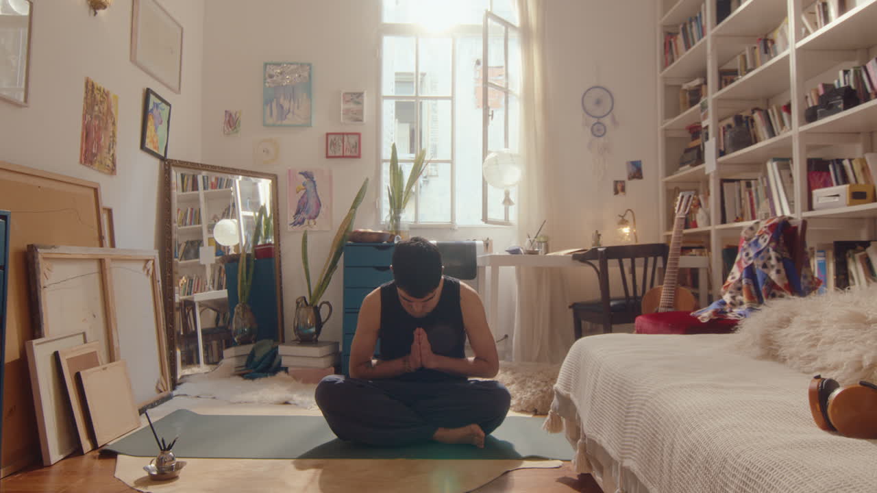 Young Man Beginning Yoga Meditation in Sunlit Room