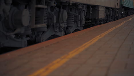 passenger train is arriving to the station. iron wheels of the train moving along the rails. close-up.