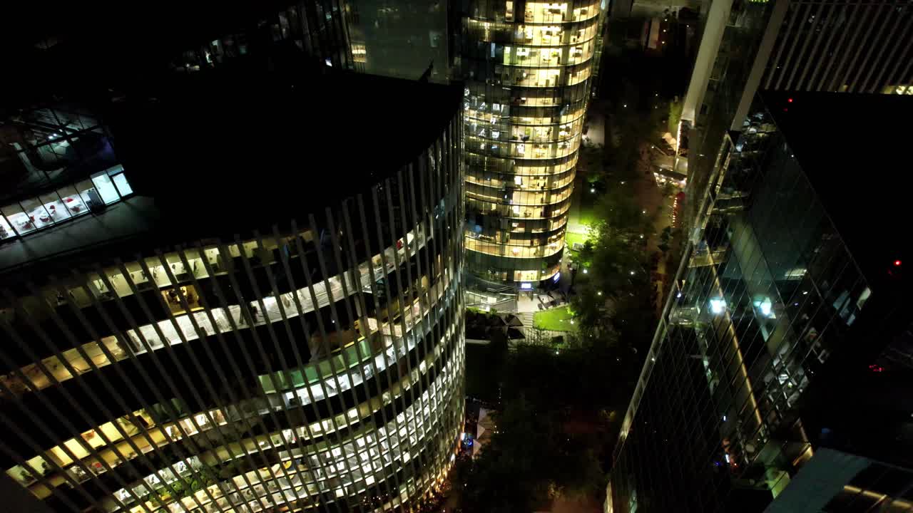drones aéreos de la noche de santiago de chile oficinas de negocios en el barrio de nueva las condes, vuelan alrededor de la arquitectura iluminada con ventanas hacia las calles de la ciudad