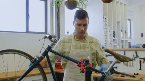 Man-repairing-bicycle-in-workshop-4k