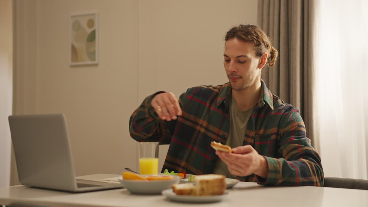 Man having breakfast while working on laptop