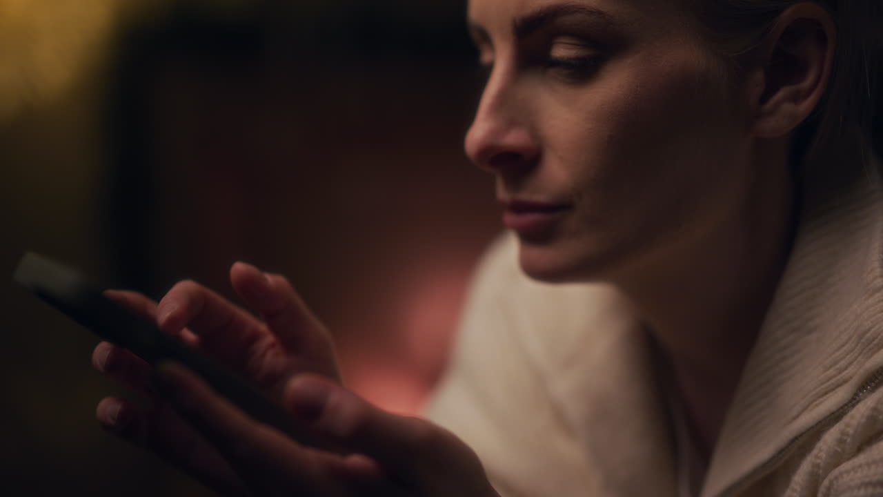 mujer sonriente navegando por las redes sociales en el teléfono inteligente por la noche