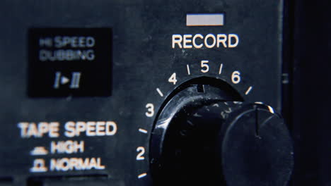 A-finger-raising-the-record-level-by-moving-a-knob-on-a-vintage-stereo-tape-recorder