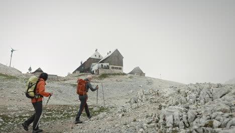 Hikers-with-backpacks-walking-towards-the-mountain-cottage