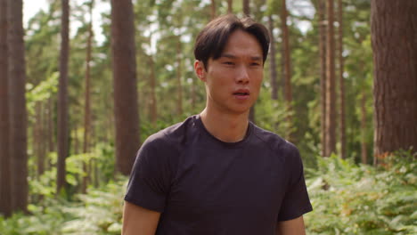 man warming up and stretching arms and shoulders before work out exercising running through forest 1