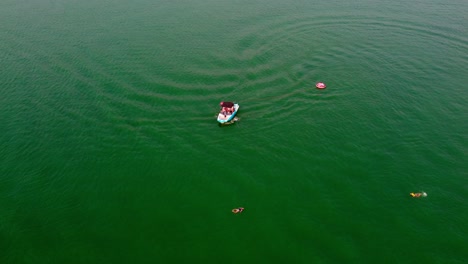 Aerial-Drone-Flyover-Boat-Returning-To-Pick-Up-Tubing-Passengers-That-Had-Fallen-Off-Their-Tube-While-Enjoying-Boating-Water-Sports-At-Bass-Lake,-California