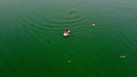 aerial drone flyover boat returning to pick up tubing passengers that had fallen off their tube while enjoying boating water sports at bass lake, california