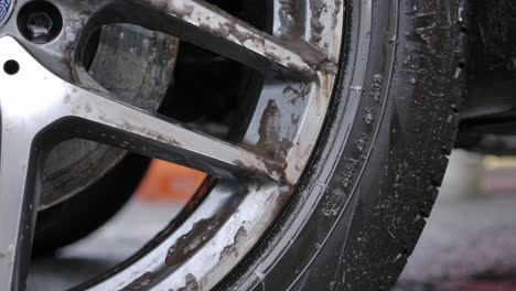 closeup of dirty car wheel with soap bubbles - car wash concept