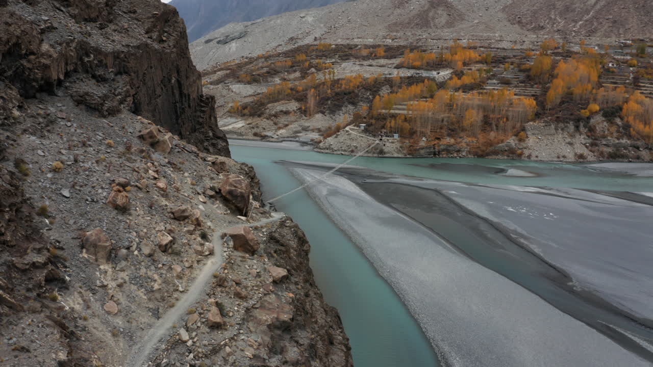 sendero de montaña que conduce al puente colgante hussaini sobre el río hunza, pakistán
