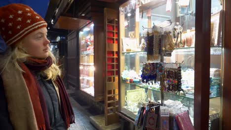 blonde woman in winter clothes looking at accessories on display outside a shop in sarajevo