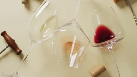 glasses with wine, corks and corkscrew lying on beige surface