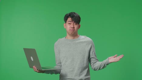 Unsatisfied Man Typing On Computer While Standing In Front Of Green Screen Background