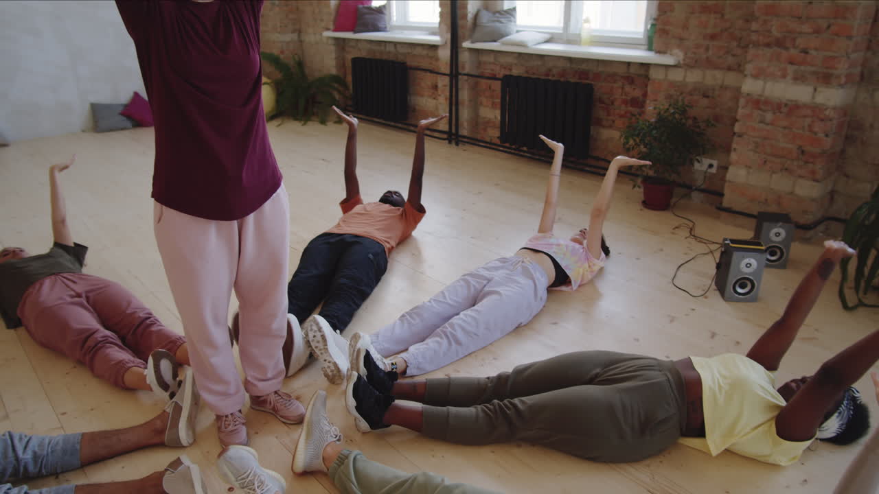 댄서들은 바닥에 누워서 선생님과 함께 손 움직임을 배우고 있습니다.