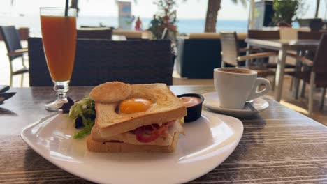 sándwich de desayuno clásico con huevo, tocino y ensalada con jugo de naranja fresco y café, brunch matutino, tiro de 4k