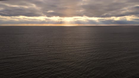 Weite-Sicht-Auf-Einen-See-Bei-Sonnenuntergang-Mit-Wolken-Und-Sonnenstrahlen,-Die-Durchscheinen