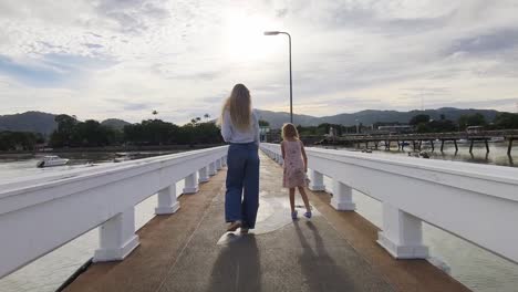 mother and daughter walking on a pier