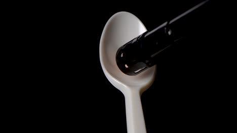 Flame-melts-hole-in-plastic-spoon-against-black-background