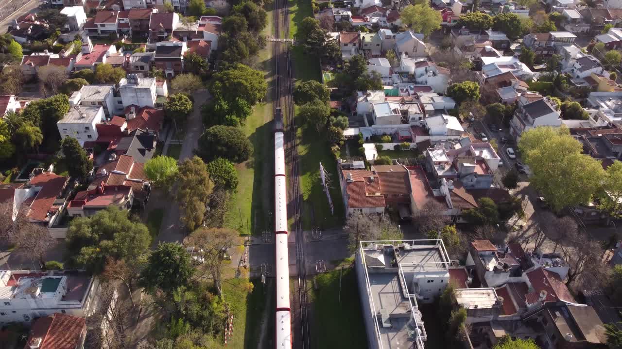 Vista aérea de trem vermelho passando por área residencial em Buenos Aires, Argentina