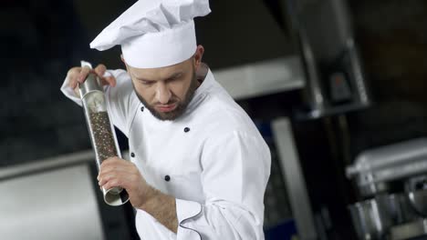 Portrait-of-chef-cooking-at-kitchen.-Closeup-chef-peppering-food-in-slow-motion