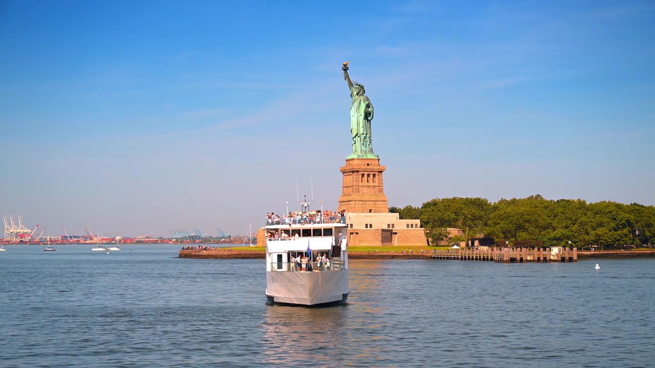 New York, USA, 4. Juli 2026: Weißes Kreuzfahrtschiff segelt vor der Freiheitsstatue. Ein großes Passagierschiff voller Menschen navigiert im Hafen nahe des grünen Monuments.