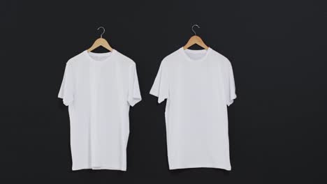 Video-Von-Zwei-Weißen-T-Shirts-Auf-Kleiderbügeln-Und-Kopierraum-Auf-Schwarzem-Hintergrund