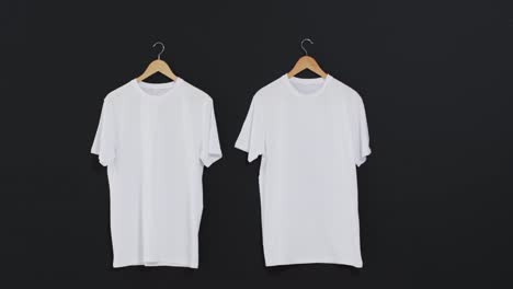 Video-of-two-white-t-shirts-on-hangers-and-copy-space-on-black-background