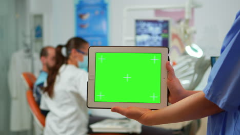 enfermera dentista sosteniendo una tableta con pantalla verde